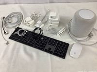 Wide view of the lot showing keyboard, mouse, HomePod, power adapters, and various cables on white surface