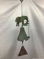 Full view of the hanging brass and copper elephant windbell showing the adult and baby elephants, the bell, and plate.