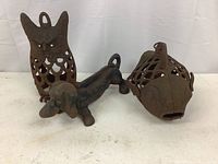 Three cast iron animal decor pieces: owl lantern, dachshund boot scraper, fish lantern
