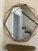 Front view showing the geometric metal frame and reflective mirror surface hung on the wall.