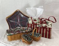 Photo of all six baskets arranged on white fabric background showing varied shapes and Christmas fabric liners.
