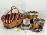 Photo showing all seven baskets arranged on white cloth background, showcasing variety of sizes and plaid liners.