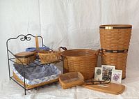 All 10 handwoven baskets and accessories arranged on white cloth background showing variety in size and styles, some with fabric linings.