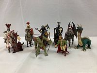 Full set of 14 medieval and fantasy figurines arranged in a row featuring dragons, knights, goblin, king and demonic woman.