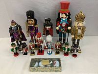 Wide view showing all 14 nutcracker figures arranged against a white backdrop with the boxed swan figurines in front.