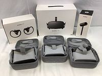 Overview of bundled items: boxed Oculus Rift headset, boxed Touch controllers, boxed sensor, and three VR headsets in cases