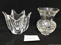 Orrefors tulip-shaped vase and Waterford etched vase side by side on black background with lot number card visible