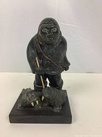 Full view of Inuit figure standing on rectangular base with two walruses.