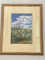 Front view of the framed photograph showing desert flora and blue sky with clouds.