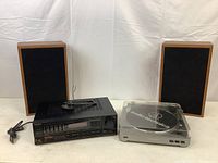 All four components grouped: two wooden speakers, black receiver, silver turntable with lid closed.