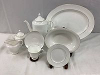 Set of various pieces including coffee pot, creamer, sugar bowl, cups, plates and a large platter, all with white bone china and gold trim.