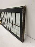 Side angle showing the black painted wooden frame with chipped paint and metal leaded glass grid