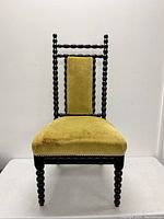 Front view of antique twisted wood spindle bobbin chair with chartreuse velvet upholstery showing seat and backrest.