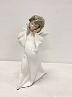 Front angle showing full white robe, angel with hands on cheeks and closed eyes, brown hair detail