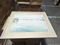 Framed watercolor painting depicting a calm marine landscape with boats and distant shoreline, signed by Richard Cheales.