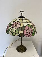 Full front view of the lamp turned off showing the floral stained glass shade and metal base.