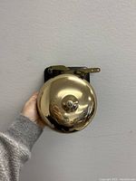 Front view of the brass dome workshop/pub bell held in hand showing polished finish.