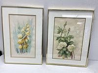 Pair of framed watercolor flower paintings by GC Padoni showing vibrant yellow and white floral arrangements.