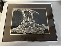 Framed monochrome print showing a hand reaching toward a candle with dripping wax, signed lower right.