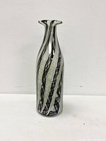 Side view of slender Murano glass vase showing black and white swirling lines in the clear glass body.