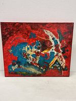 Front view of abstract mixed media painting with dominant red, blue, and white textures.