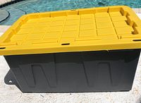 Side view of the storage container showing black base with yellow lid and hand grips