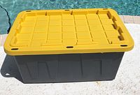 Front view of 27 Gal Tough Box construction grade storage container with yellow lid and black base.