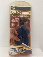 Front view of sealed blister pack showing DAP Pro Caulk 4 Piece Caulking Tool Kit with hand demonstrating tool use on packaging.
