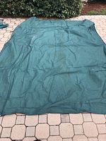 Turquoise canvas tarp spread on outdoor surface showing overall size and condition.