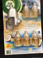 Photo showing Air Wick Tropical Collection packaging containing 1 white plug-in oil warmer and 6 scented oil refill bottles (3 Tropical Bliss, 3 Serene Coconut Breeze) with coconut and tropical themed graphics.