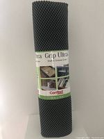Photo of rolled Con-Tact Grip Ultra shelf and drawer liner in dark grey with label showing brand and measurements.