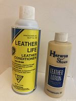 Photo showing two bottles: a yellow aerosol can of Leather Life Leather Conditioner and an 8 oz plastic bottle of Harwyn Shoes Leather Lotion with white caps.