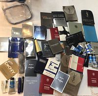 Top view of assorted men's cologne samples mostly in sachets and small vials, showing multiple brand names and packets arranged loosely