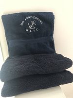 Photo showing three navy blue bath towels stacked with one prominently displaying embroidery for 10th Anniversary West Babylon Yacht Club