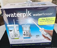 Front of box showing product images, brand name, and features of Waterpik Waterflosser set.