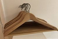 Photo showing a set of wooden hangers stacked together with visible metal hooks and wooden bottom bars.