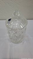 Clear 7 inch lead crystal jar with lid, showing one side view with intricate star and fan handcut designs and a pointed knob lid