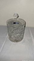 Front view of closed crystal vanity jar showing detailed hand-cut starburst and geometric pattern and faceted knob lid.