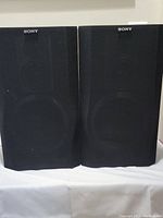Front view of pair of Sony SSD1-70 speakers with black fabric grills and Sony logos visible on top center of grills.