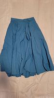 Photo of a medium blue vintage style skirt, pleated with flowy fabric