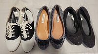 Photo showing three pairs of women's shoes: black and white Predictions sneakers, blue embellished Kelsi Dagger flats, and black sparkle Mossimo flats.
