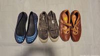 Photo showing three pairs of women's size 10 shoes: blue Crocs flats, brown Keds slip-ons, and tan Pikolinos leather flats with perforated designs and straps.