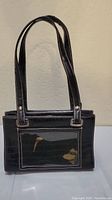 Front view of small black women's handbag with clear vinyl front pocket and two handles