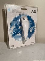 Photo of one brand new Nintendo Wii Nunchuk controller in original packaging showing front blister pack with blue and white card, Wii and Nintendo logos and controller visible.