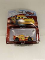 Photo of new in package Hot Wheels diecast car model of Miguel Camino from Disney Pixar Cars movie, showing front of packaging and car visible in bubble blister pack.