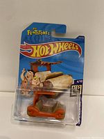 Front view of the Hot Wheels Flintstones car in blister packaging showing the car and graphic card with characters and branding