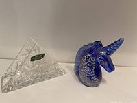 Clear crystal triangular glass napkin holder with starburst cut design, Czechoslovakia label visible, placed next to blue-purple glass unicorn figurine.