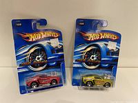 Two Hot Wheels 1968 Mustang cars, one red and one yellow, in original blister packaging with blue backing cards and Hot Wheels logos.