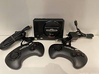 Front view of Sega Genesis Classic console with two wired controllers, power adapter, and HDMI cable laid out.