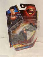 Front view of Superman action figure and motorcycle in original blister packaging with Man of Steel branding.